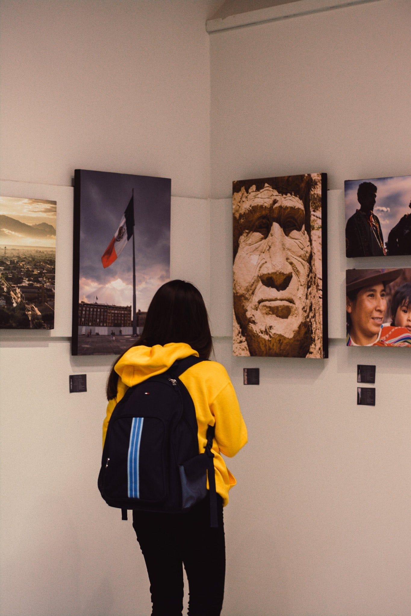 Alumna viendo una exposición fotográfica en la Galería Eleanor Jackson, en la Escuela de Artes y Comunicación.